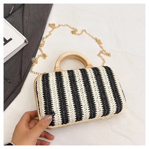 Detail of hand-woven striped straw handbag with wooden handle and gold chain strap
