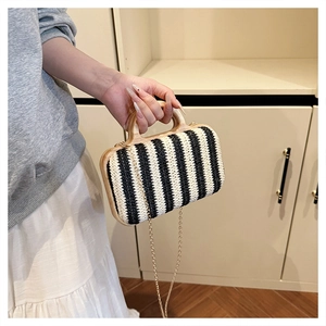 Detail of hand-woven striped straw bag with wooden handle and gold metal chain strap