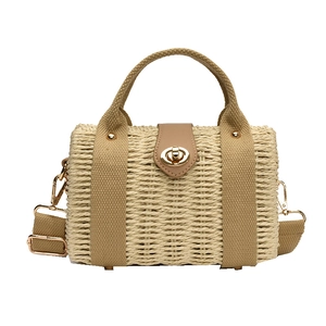 Woven straw tote bag with brown fabric handles and gold twist lock on white background
