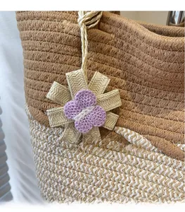 Detailed view of handmade straw flower and purple woven butterfly charm on tote bag