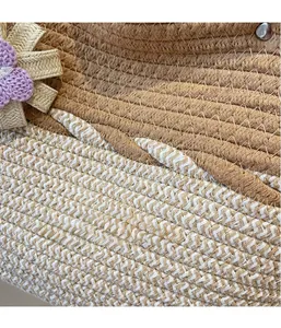 Macro detail of woven straw tote bag with metallic threads and a decorative floral accent