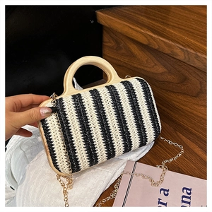 Detail of striped straw bag with round wooden handle and gold metal chain strap