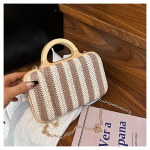 Detail of handmade striped straw bag with round wooden handles and gold chain strap