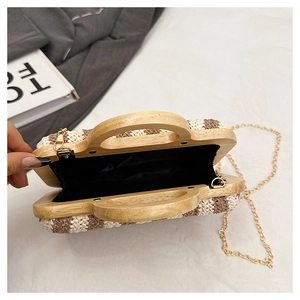 Detail of woven straw handbag with wooden handle, metal hinges and black fabric lining