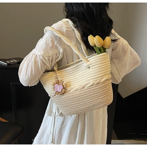 Detail of woven tote bag with flower pendant and tulip decoration on shoulder