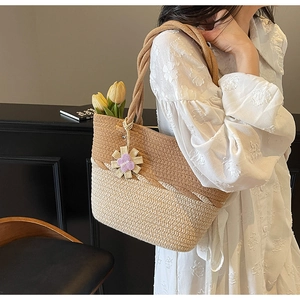 Macro detail of hand-woven bicolor tote bag with purple daisy butterfly pendant accessory