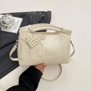 Elegant off-white crossbody bag with woven handle, pearl heart charm and lace details