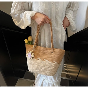 Detail of woven straw tote bag with contrast colors and a floral charm accessory
