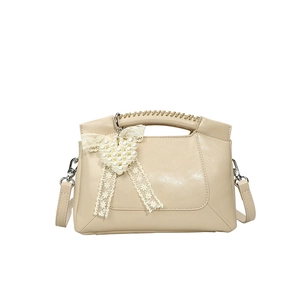Creamy beige small crossbody bag with woven handle and pearl heart bow accessory