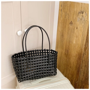 Vue détaillée du sac panier tressé noir avec maille ajourée et finition brillante