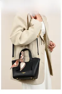 Side view of a black pebble leather bucket bag with a stylish geometric print silk scarf