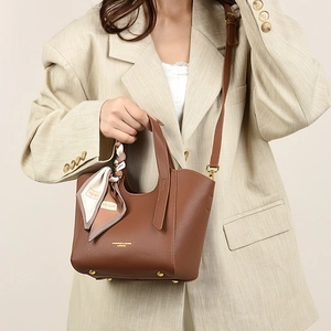 Detail of brown litchi leather tote bag with silk scarf and golden protective feet
