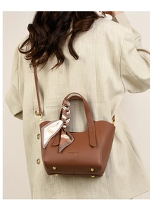 Close-up of brown litchi pattern bucket bag with decorative silk scarf on handle