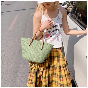 Street style shot of a mint green woven tote bag with brown leather handles and adjustable straps