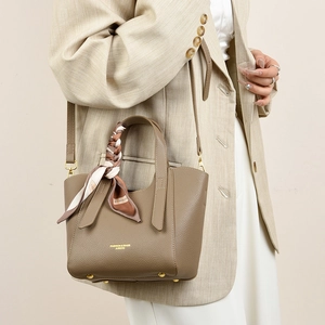 Close-up of khaki pebbled leather tote with printed silk scarf wrap on handle and gold text