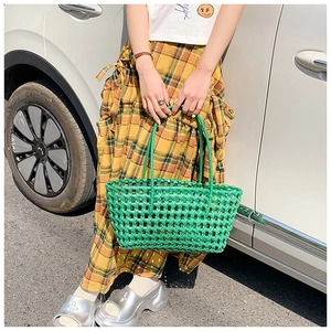 Détail du sac panier tressé vert vif avec motif ajouré et poignées à double usage