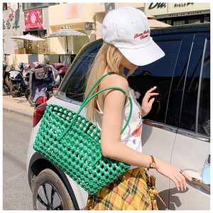 Sac fourre-tout tissé vert avec bandoulière porté en extérieur pour l'été
