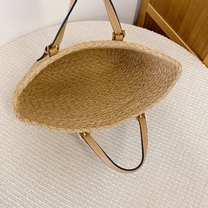 Detail of spacious straw tote bag interior with adjustable leather handles and metal buckle