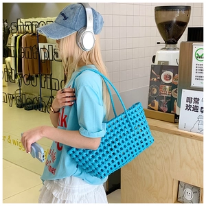 Détail du sac cabas bleu vif tressé avec motif damier ajouré et deux poignées