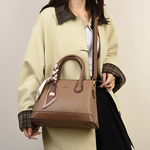 Brown litchi pattern handbag with golden logo and decorative striped silk scarf detail