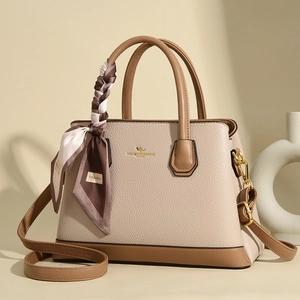 Detailed view of beige litchi leather handbag with kangaroo logo and decorative silk scarf