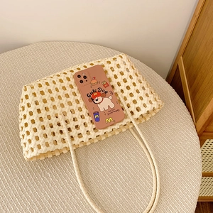 Détail d'un sac à bandoulière tressé creux avec coque de téléphone chien cartoon