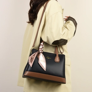 Close-up of black litchi leather tote with brown handles and a decorative silk scarf