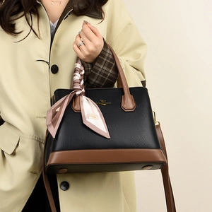 Close-up of litchi grain faux leather bag with contrast handle and pink silk scarf detail