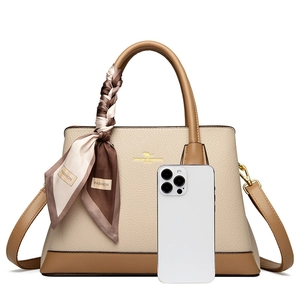 Close-up of litchi texture leather handbag with golden logo and decorative scarf