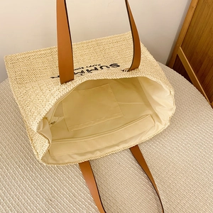Detail view of woven straw tote bag interior with zipper closure and leather handles