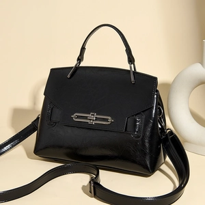 Détail du sac à main noir en cuir froissé brillant avec boucle métallique argentée sur le rabat
