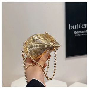 Detail of champagne gold shell clutch bag with fine horizontal texture and bead chain