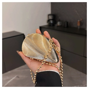 Close-up of golden shell-shaped evening clutch with pleated texture and bead chain