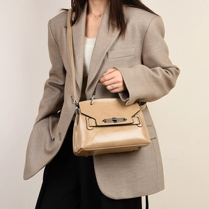 Détail du sac à main en cuir verni kaki avec boucle porté avec un blazer beige