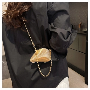 Close-up of golden shell-shaped acrylic clutch bag with round bead metal chain strap