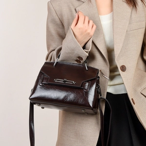 Détail macro du cuir ciré marron foncé et de la boucle argentée sur le sac à bandoulière