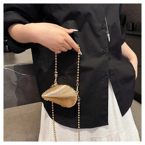 Close-up of a gold shell-shaped acrylic evening bag with fine horizontal metallic ribbing