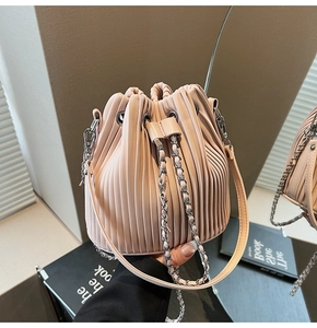 Detail of light pink bucket bag with pleated texture and silver chain strap