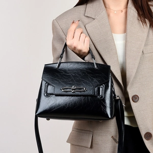 Détail d'un sac à main noir brillant plissé avec boucle en métal et blazer kaki
