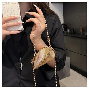 Detail of mini gold evening bag with metallic pleated shell design and chain strap