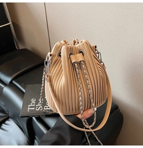 Detail of apricot pleated bucket bag with silver chain and drawstring closure