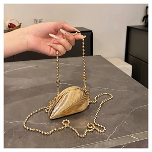 Detail of a gold shell evening clutch with pleated texture and a delicate beaded metal chain