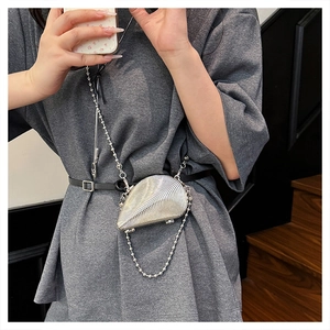 Close-up of metallic shell-shaped clutch bag with beaded chain and textured silver surface