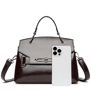 Détail du sac à main brillant marron foncé avec poignée en métal et téléphone témoin