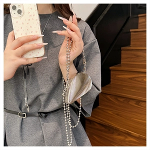 Close-up of shell-textured silver acrylic clutch bag with delicate bead chain strap
