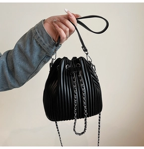 Close-up of black pleated bucket bag with silver metal chain and drawstring detail