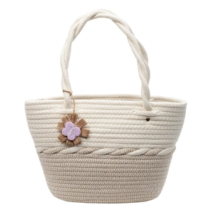 Woven tote bag with two-tone design, knotted handles and decorative floral pendant
