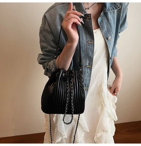 Detail of black pleated bucket bag with silver chain drawstring and leather shoulder strap