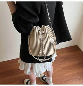 Detail of cream pleated bucket bag with silver chain strap and drawstring closure