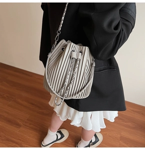 Detailed view of women's grey bucket bag with pleated design and silver chain strap